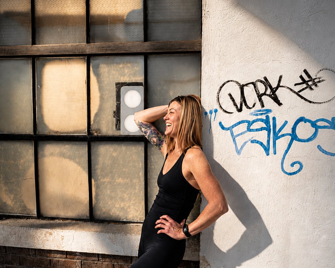 Lindsey Estes leaning against a painted brick wall